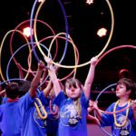 Young children play with hoola-hoops on stage