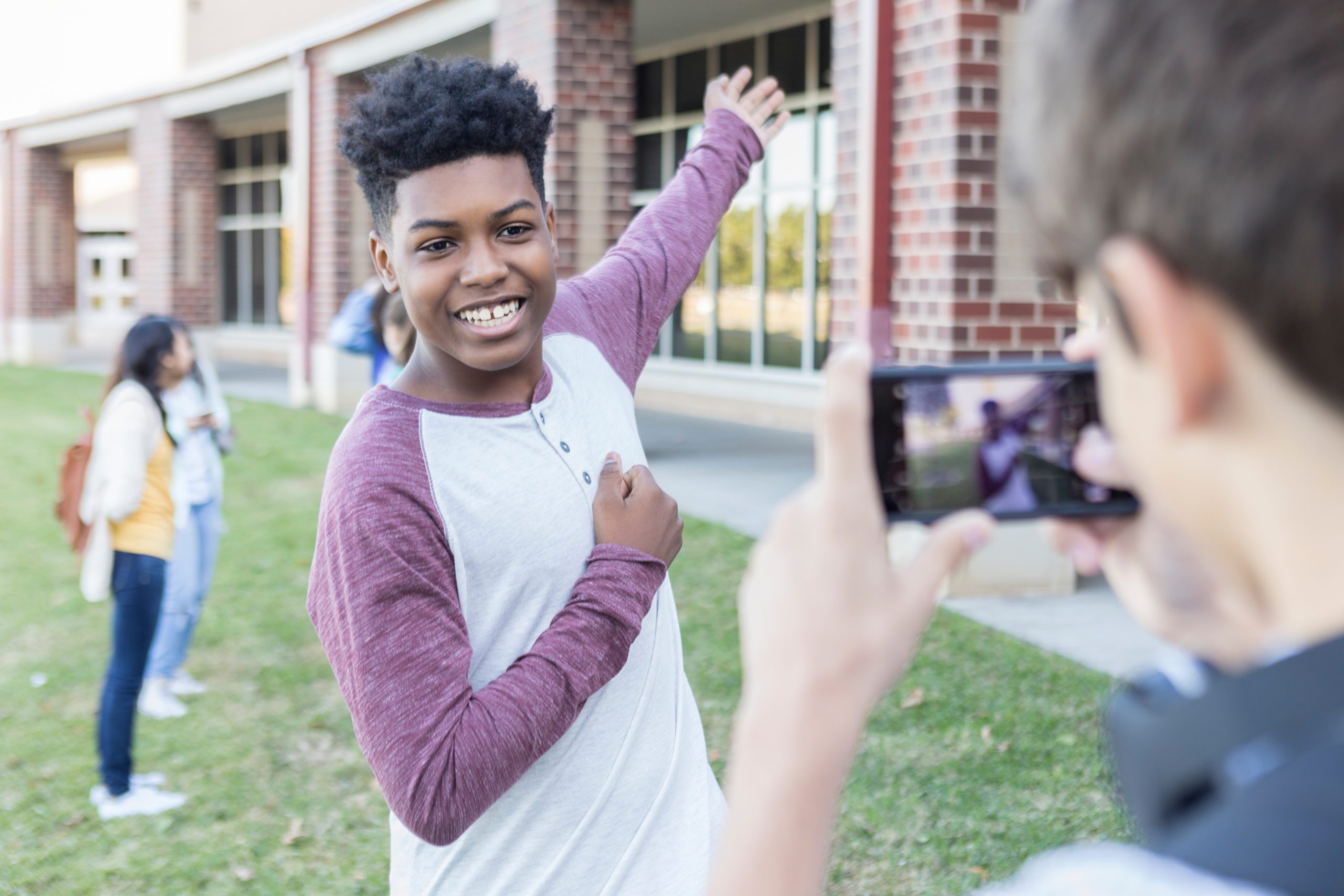 Teenage boy taking photo outside high school on campus
